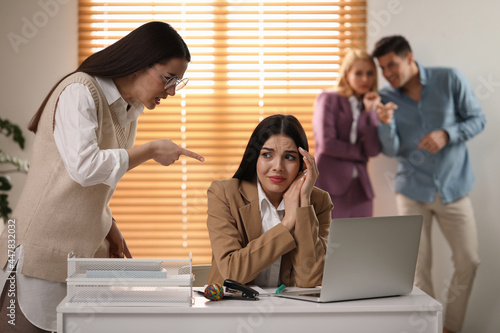 Woman scolding employee at workplace in office photo