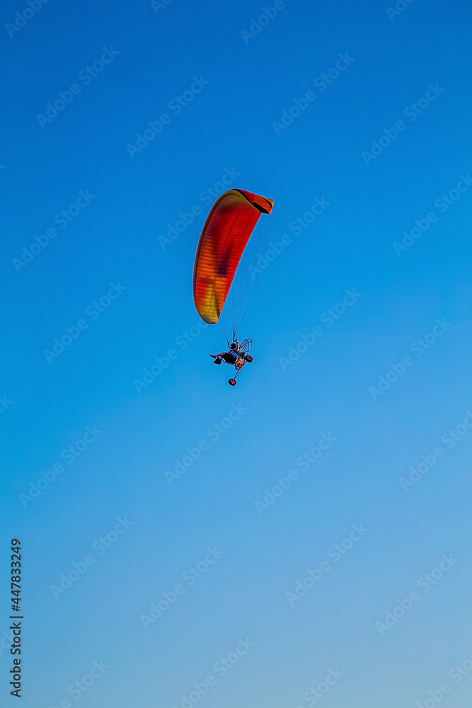 paraglider flying with paramotor on air on evening against the blue sky paraglider flying with paramotor on air on evening against the blue sky
