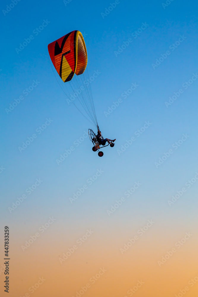 Israel, Haifa, - Jule 1, 2021: paraglider flying with paramotor on air on evening against the blue sky Israel, Haifa, - Jule 1, 2021: paraglider flying with paramotor on air on evening against the blue sky