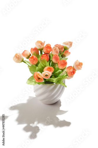 Subject shot of creamy orange tulips in little white ceramic pot. Fine faux flowers for interior design are isolated on the white background. 
