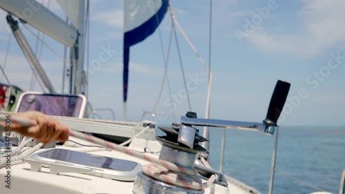 Close Up of Sailman Hands Unwinding Rope From Winch of Sailboat on Sunny Tropic Day, Slow Motion Full Frame photo