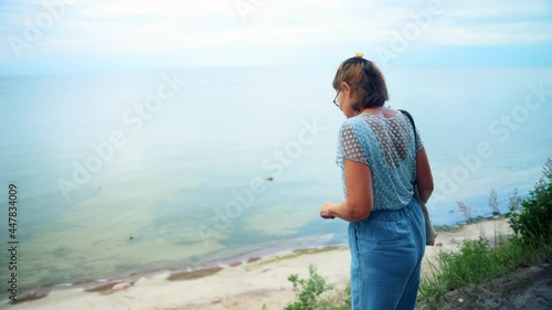 Backview Of A Lady Walking On Coastal Cliffs Overlooking Seascape, Of Karkle, Lithuania. - Tracking Shot photo