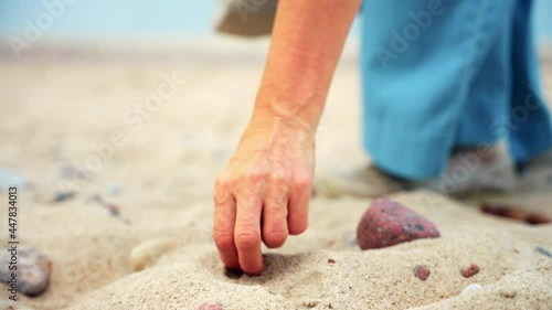 Mid Adult Woman Collecting Stones On Sandy Waterfront In Karkle Beach, Lithuania. - Close Up Shot photo