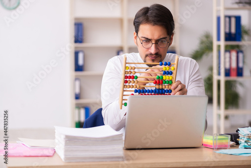 Young male bookkeeper in budget planning concept holding abacus photo