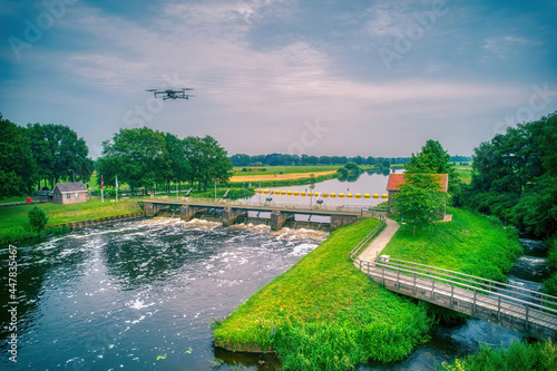 Water swirls from the weir in the river Vecht in the Netherlands. Fish passage, fish ladder to the right of the water, Overijsselse Vecht, A flying drone in the blue sky
