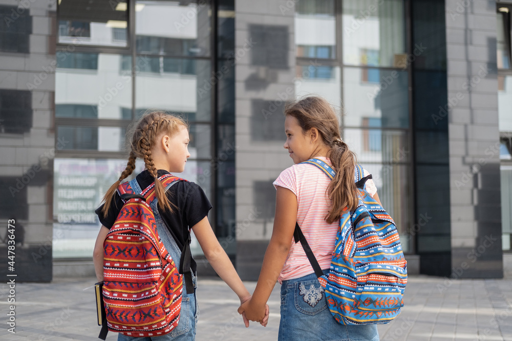  Two girls with backpack go to school and talk together 
