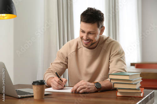 Man with laptop and books studying at table in library