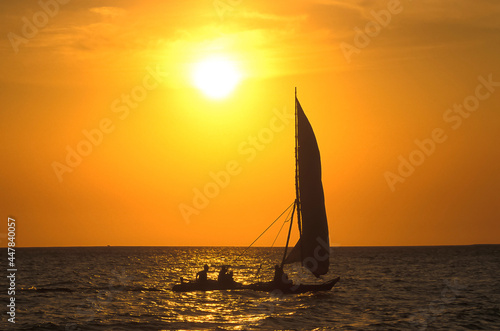Paysage en mer avec bateau, voilier dans une ambiance jaune orange du coucher de soleil.