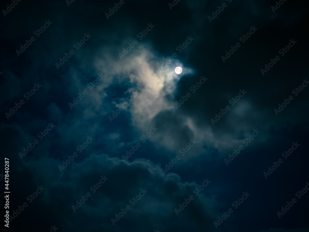 Fototapeta premium Full moon among clouds in the night sky.