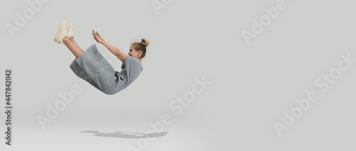 Studio shot of little preschool caucasian girl in casual clothes falling down isolated over white studio background. photo