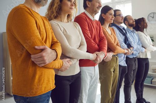 Group of diverse people of different ages standing in row and holding hands. Team of multiracial multi generational colleagues or community members showing unity and support