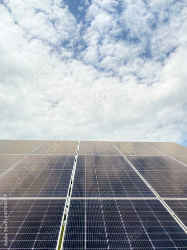 Solar energy panels against blue sky with clouds