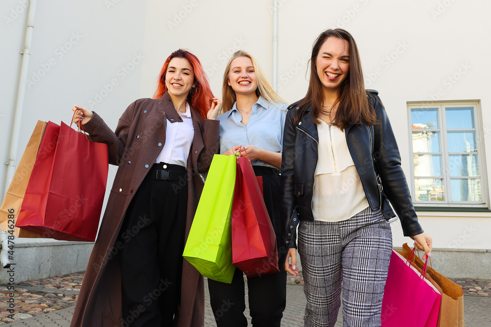 Three young female friends with colorful bags after shopping