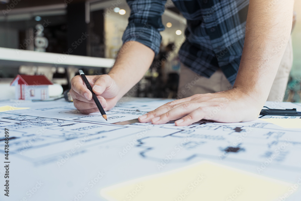 Interior designer or architect reviewing blueprints and holding pencil drawing on desk at home office. Interior designer or architect reviewing blueprints and holding pencil drawing on desk at home office.