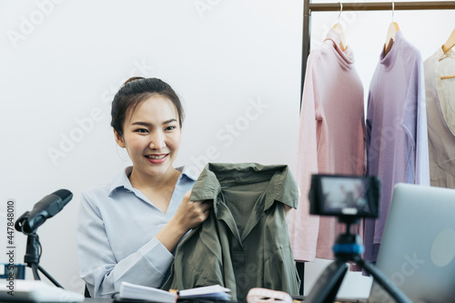 Young asian entrepreneurs are picking up their clothes to show off to customers through online sales on a live phone. photo