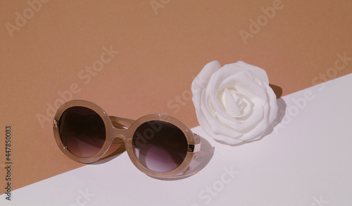 Minimal fashion still life scene. Trendy accessory sunglasses and roses in white beige space. Shopping and sale concept. Stylish details in look