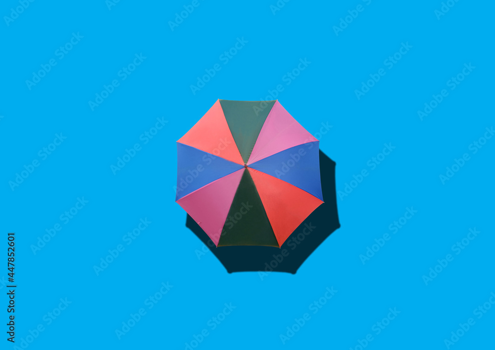 Obraz premium Top view, Single rainbow umbrella isolated on cyan background for stock photo or design, invesment, business, summer concept