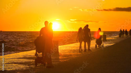 SILHOUETTE: Tourists walk up and down a scenic coastal promenade at sunset.