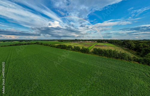 Aerial panorama view shot with drone of a rainbow over stormy sky. Rural landscape with rainbow over dark stormy sky in a countryside at summer day. High quality photo