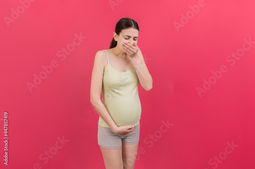 Fototapeta Naklejka Na Ścianę i Meble -  Pregnant woman suffering from toxicosis. Toxicosis Of Pregnancy. Pregnant Lady Feeling Sick Having Nausea Standing On Colored isolated Background. Free Space