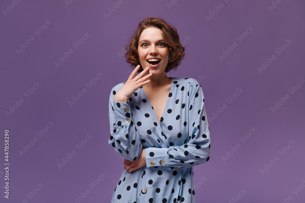 Portrait of excited lady looking into camera. Gorgeous young ginger in stylish blue dress joyfully posing isolated over purple background Portrait of excited lady looking into camera. Gorgeous young ginger in stylish blue dress joyfully posing isolated over purple background