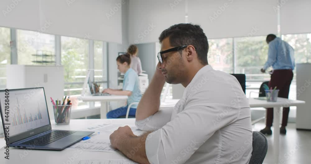 Side view of tired indian businessman falling asleep over laptop computer on desk Side view of tired indian businessman falling asleep over laptop computer on desk