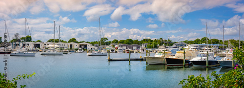 Tranquil marina landscape with moored ships under dramatic clouds in Falmouth on Cape Cod. © Naya Na