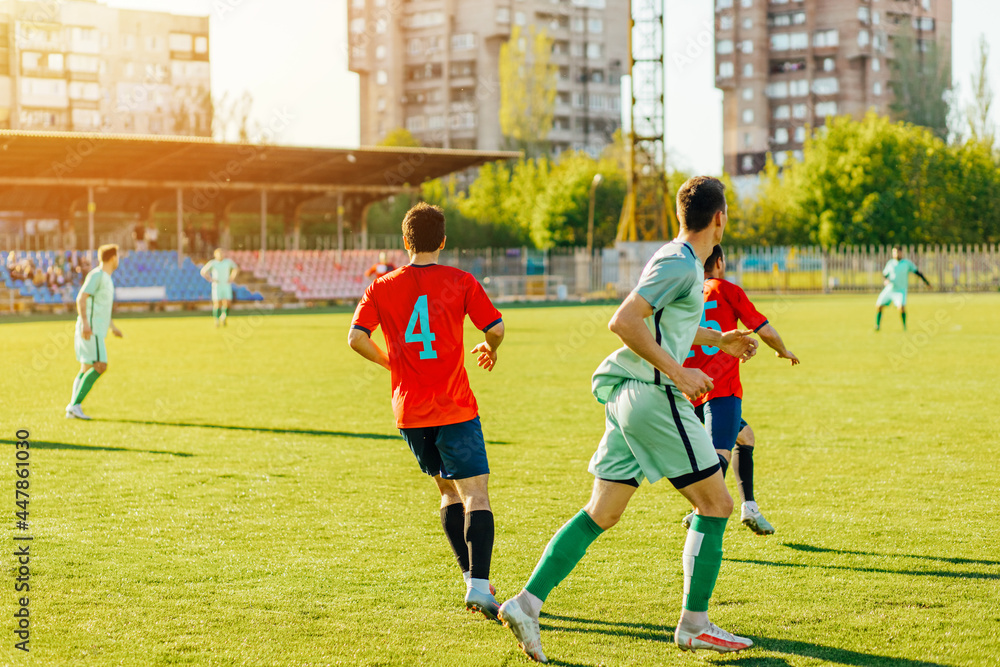 Obraz premium football players in action at the stadium, Football game for adults, Players of two teams competing for the ball