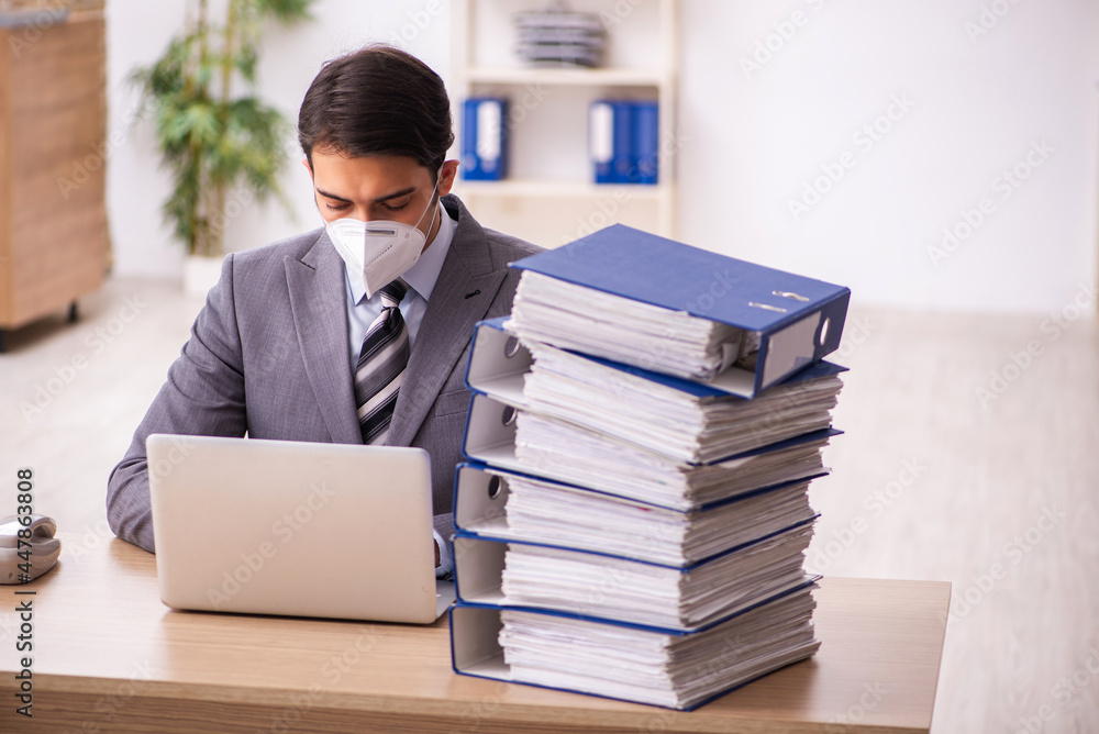 Young male employee working at workplace during pandemic Young male employee working at workplace during pandemic