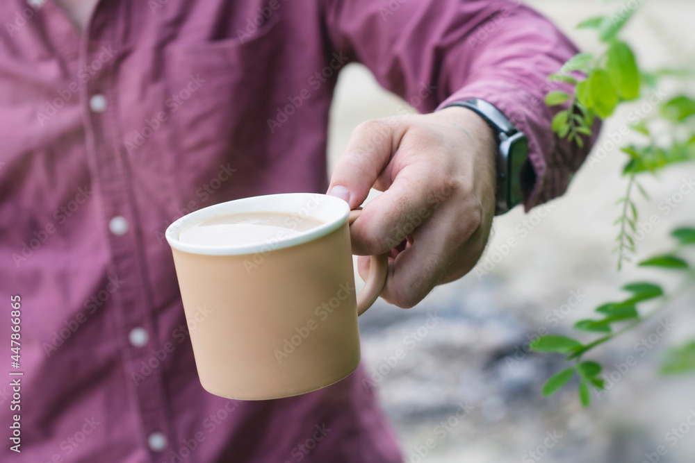 Man holds a mug with coffee in his hands on the background of nature. Man holds a mug with coffee in his hands on the background of nature.