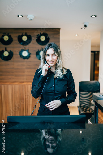 Beautiful young woman working at hotel reception or check out