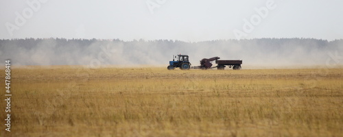 Harvested linen field panorama with tractor harvester trailer,  linum harvesting at summmer day, European farm landscape