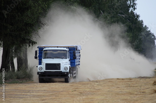 Russian truck fast drive in dust cloud on linen field edge  linum harvesting in East Europe at summer day