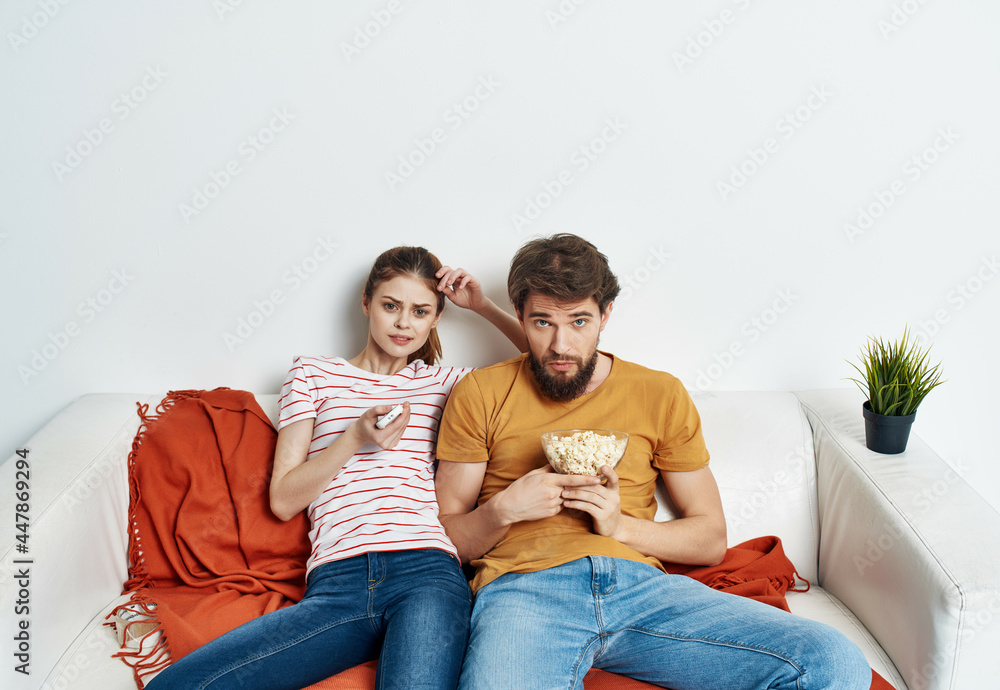 young couple with popcorn sitting on the couch watching movie entertainment young couple with popcorn sitting on the couch watching movie entertainment