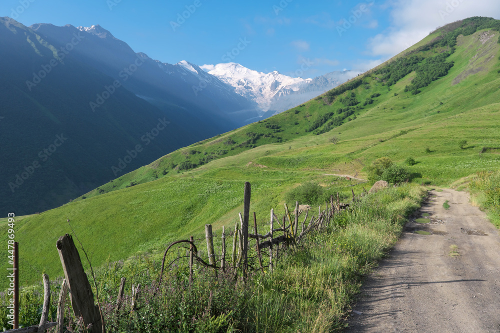 View of the road in Genaldon river gorge and Mayly glacier on sunny summer day. North Ossetia–Alania, Caucasus, Russia.