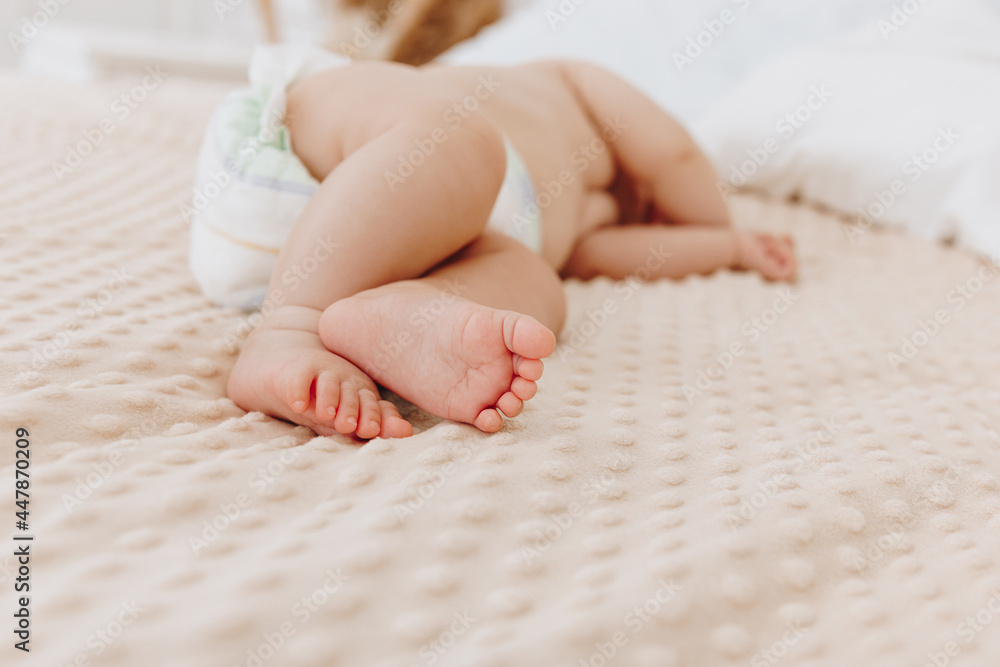 Newborn baby in diaper lying on bed
