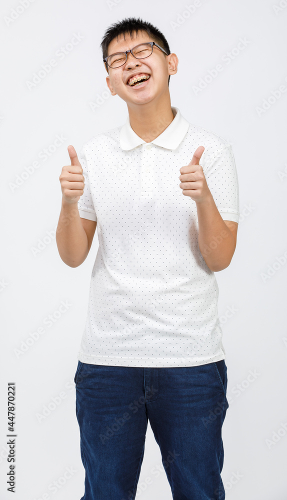 Portrait shot of handsome smiling young boy teenager wearing eyeglasses looking to the camera and showing thumbs up with fingers isolated on white background in the studio. Concept of success. Portrait shot of handsome smiling young boy teenager wearing eyeglasses looking to the camera and showing thumbs up with fingers isolated on white background in the studio. Concept of success.