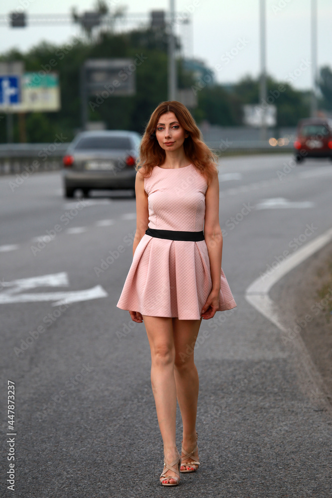 Alone beautiful woman in pink dress standing at the road Alone beautiful woman in pink dress standing at the road