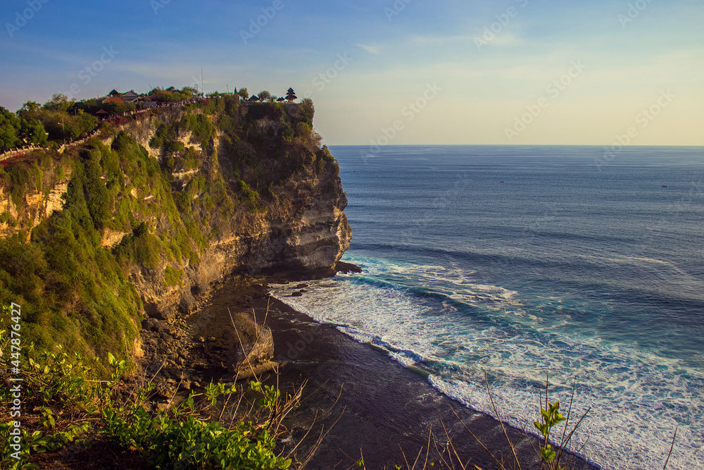 Aerial view of Pura Luhur Uluwatu Temple, Bali island, Indonesia. Beautiful landscape on sunset. Uluwatu is famous Balinese sea temple, popular attraction for tourists. Travel and vacation concept