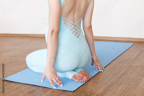 pregnant sits with her back on a sports mat on a light background. close-up. yoga for pregnant women