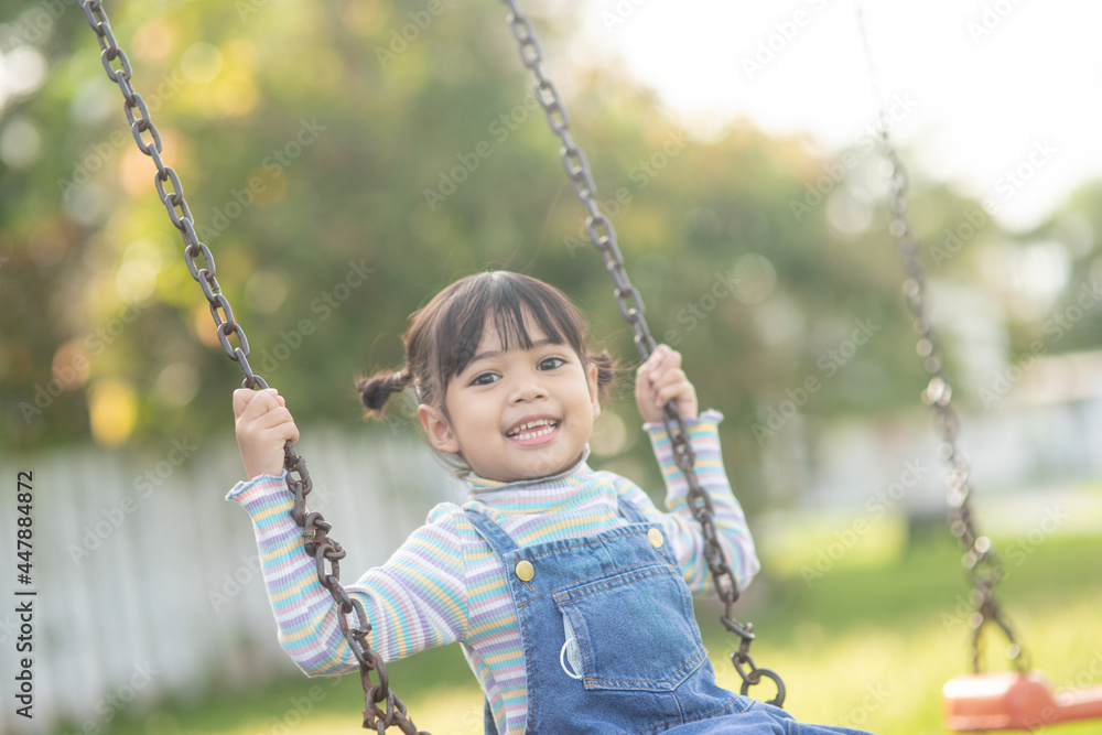 Happy little Asian girl playing swing outdoor in the park Happy little Asian girl playing swing outdoor in the park