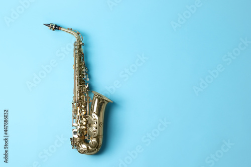 Beautiful saxophone on light blue background  top view. Space for text