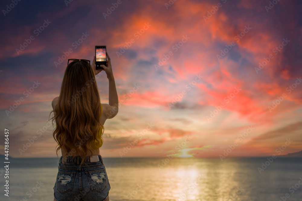 Fototapeta premium woman shootting photo on the beach at sunset