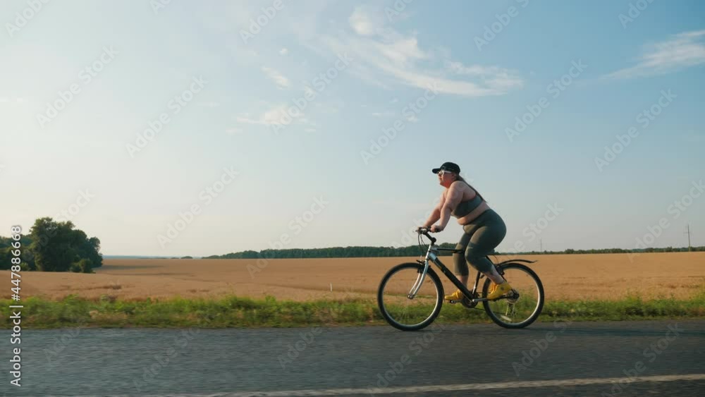 Young obese woman shedding excess weight while riding a bicycle on the road in the countryside Young obese woman shedding excess weight while riding a bicycle on the road in the countryside