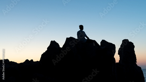 Man practicing yoga at sunset stock photo. Young man relaxing by the sea at sunset. 