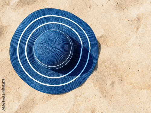 large blue straw hat on the sand, copy space. Beach holiday concept