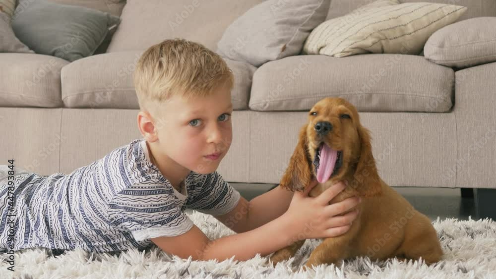 Pretty child boy lying on the floor and hugs little cocker spaniel puppy dog Pretty child boy lying on the floor and hugs little cocker spaniel puppy dog