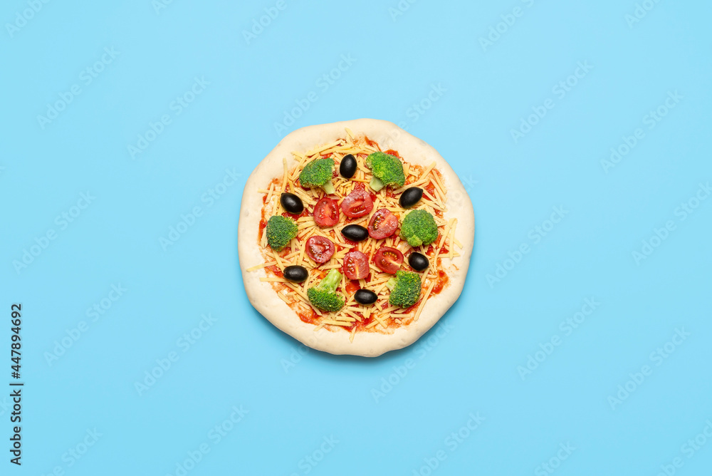Fototapeta Vegetarian pizza uncooked on blue table. Raw vegan pizza, flat lay