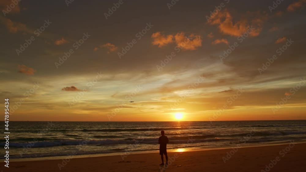 stunning colorful clouds in yellow sky at sunset..A man flying drone in stunning colorful yellow sky at sunset..Tourists piloting drones to take pictures of beautiful sunset. stunning colorful clouds in yellow sky at sunset..A man flying drone in stunning colorful yellow sky at sunset..Tourists piloting drones to take pictures of beautiful sunset.