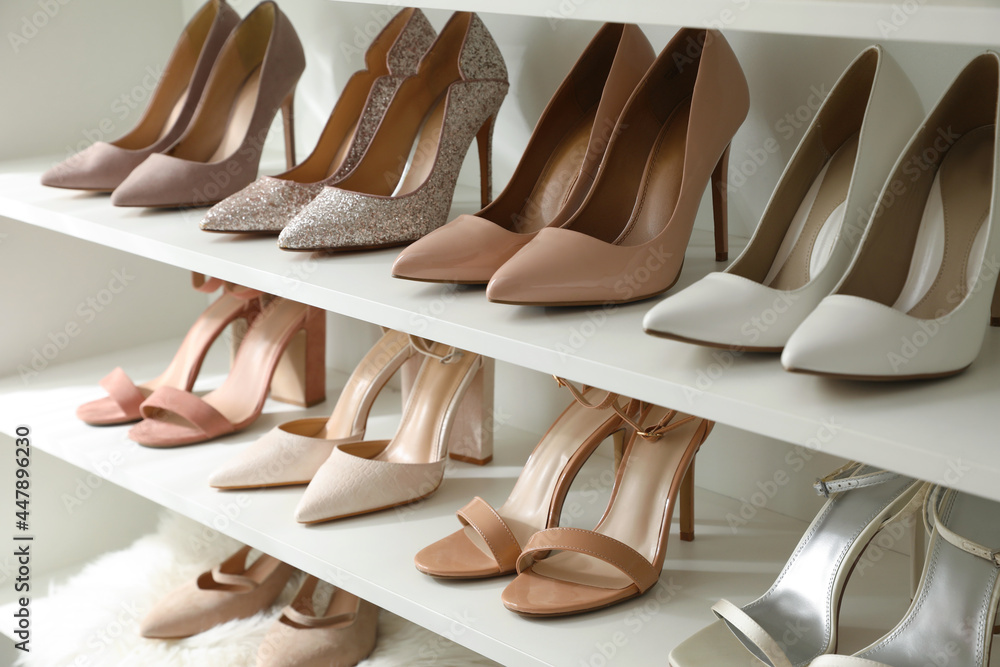Different stylish women's shoes on shelving unit - obrazy, fototapety, plakaty 